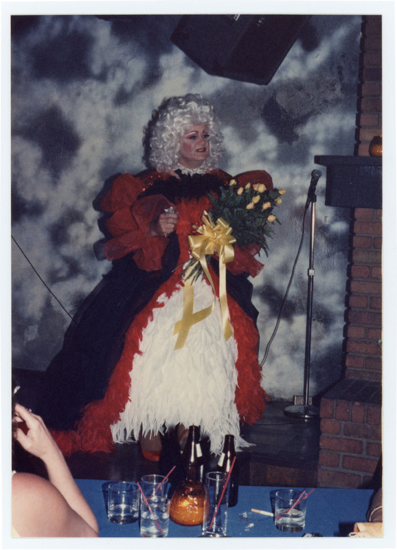 Drag performer on stage with bouquet
